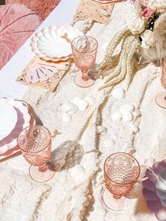 a table topped with lots of pink and white plates covered in lace next to a vase filled with flowers