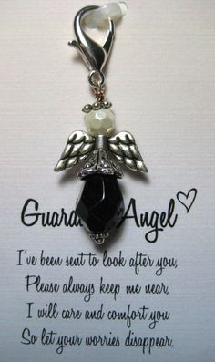 a necklace with an angel charm hanging from it's side on top of a piece of paper