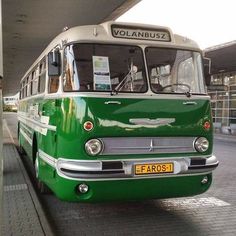 an old green bus parked in front of a building