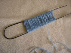 a piece of blue yarn sitting on top of a bed next to a pair of scissors