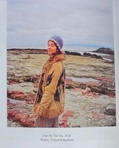 a woman standing on top of a rocky beach