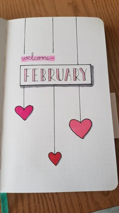 an open notebook with some hearts hanging from it's strings and the words welcome february