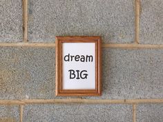 a sign that says think big on the side of a brick wall next to a wooden frame