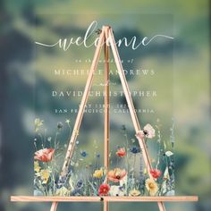 a wooden easel with flowers and the words welcome on it