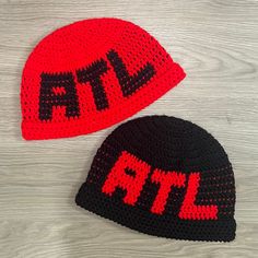 two crocheted hats sitting on top of a wooden table next to each other