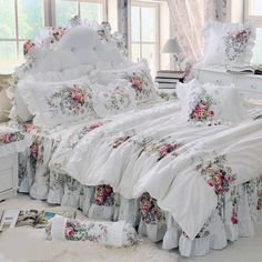 a white bed sitting in a bedroom next to a window with lots of pillows on top of it