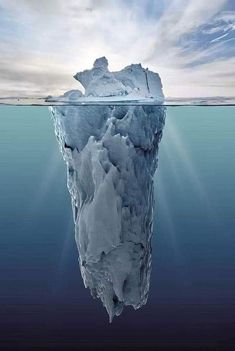 an iceberg floating in the ocean with sunlight shining on it's surface and water around it