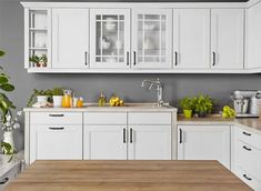 a kitchen with white cabinets and wooden counter tops in front of a green framed wall