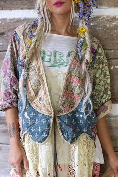 a woman with flowers in her hair standing next to a wooden wall wearing a jacket