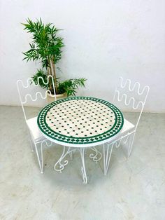 a table and two chairs sitting in front of a potted plant on the floor