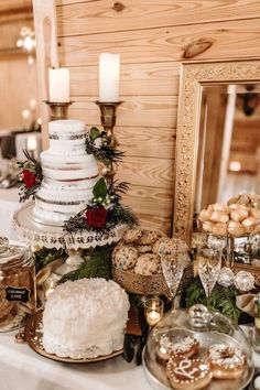 a table topped with a white cake and lots of desserts next to a mirror