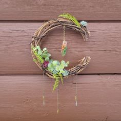 a wreath is hanging on the side of a wooden wall with flowers and greenery