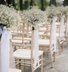 the aisle is lined with chairs and decorated with baby's breath flowers, tied in white ribbon