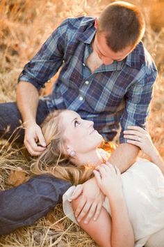 a man kneeling down next to a woman laying on the ground with her arm around him