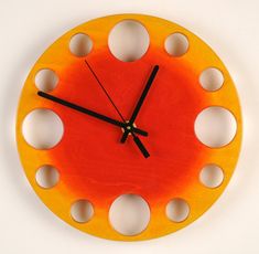 an orange and yellow clock with holes in the middle on a white background, it looks like something out of space