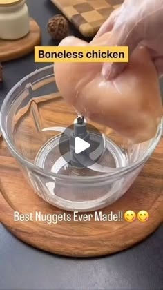 someone is adding ingredients to a chicken in a glass bowl on a wooden cutting board