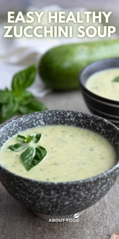 two bowls filled with soup and garnished with basil leaves, on top of a table