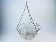 a metal basket hanging from a chain on a white background with no people around it