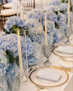 the table is set with blue hydrangeas and gold place settings for dinner guests