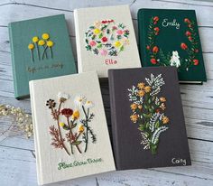 four embroidered notebooks with flowers on them