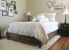 a bedroom with white bedding and pictures on the wall