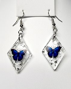 Introducing our Blue Diamond Butterfly Resin Earrings - a mesmerizing and enchanting accessory that brings the beauty of butterflies to life. Handmade with meticulous care, these 1-inch diamond-shaped earrings feature captivating blue butterflies suspended in clear resin, enhanced with a sprinkle of glitter for added allure. The silver earrings hooks provide a sleek and elegant finish, making these earrings a versatile choice for both casual and more formal occasions. Embrace the serene charm of azure blue and the delicate elegance of butterflies with each wear. Elevate your style with the Blue Diamond Butterfly Resin Earrings - a celebration of nature's grace and the art of handmade craftsmanship. Let these earrings become a standout piece in your collection, adding a touch of ethereal be Diamond Shaped Earrings, Elegant Blue Butterfly Jewelry, Blue Butterfly Sterling Silver Jewelry, Butterfly Shaped Diamond White Jewelry Gift, Diamond White Jewelry With Butterfly Charm For Gift, Blue Butterfly Charm Dangle Earrings, Blue Dangle Earrings With Butterfly Charm, Blue Butterfly Charm Earrings For Gift, Handmade Blue Butterfly Earrings