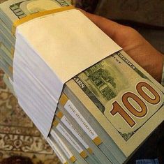 a person is holding stacks of money in their left hand, with one hundred dollars on the other