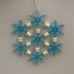 a snowflake ornament hanging from a string on a gray background with white and blue beads