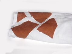 an orange and white towel on top of a white tablecloth with two brown triangles