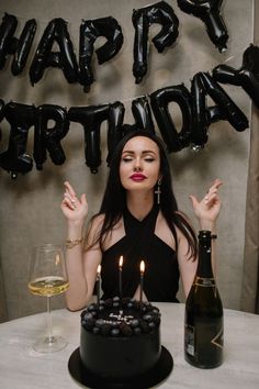 a woman sitting at a table in front of a birthday cake with candles on it