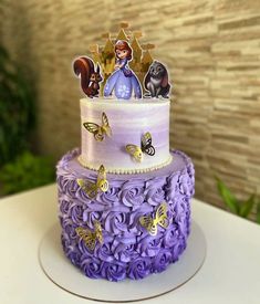 a three tiered cake with purple frosting and decorations