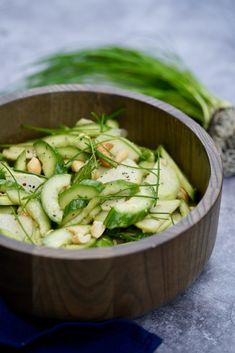 a wooden bowl filled with cucumbers and green onions on top of a table