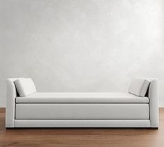 a white couch sitting on top of a hard wood floor next to a wall in an empty room