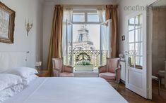 a bedroom with a bed, chair and window overlooking the eiffel tower