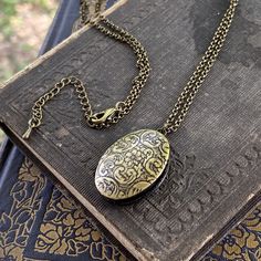 Oval vintage style locket. It is antiqued brass and the inside is quite a bit darker. On 28 inches of antiqued brass chain. Vintage Etched Oval Pendant Locket Necklace, Antique Brass Locket Necklace With Oval Pendant, Vintage Brass Locket Necklace With Oval Pendant, Vintage Charm Oval Pendant Locket Necklace In Brass, Ornate Bronze Locket Necklace With Antique Finish, Bronze Oval Locket Necklace, Bronze Oval Pendant Locket Necklace, Vintage Oval Pendant Locket Necklace With Antique Finish, Handmade Vintage Oval Pendant Locket Necklace