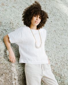 a woman leaning against a rock with her hand on her hip