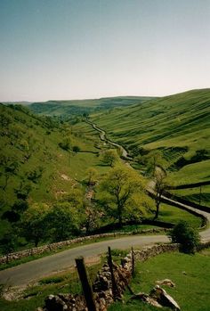 a winding road in the middle of a lush green valley