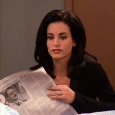 a woman sitting at a table reading a newspaper