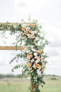 an outdoor wedding ceremony setup with flowers and greenery on the side of the aisle