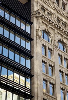 a large building with many windows and a clock on it's side, next to another tall building