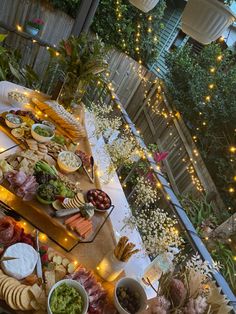 a table filled with lots of food on top of a wooden table covered in lights