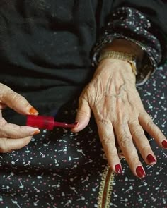 an older woman with red nails is holding her hand out to the other side of her body