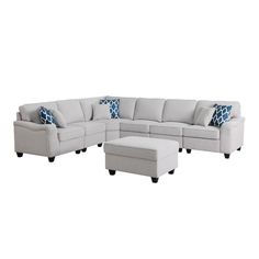 a large sectional couch with blue pillows on the back and footrests, sitting in front of a white background