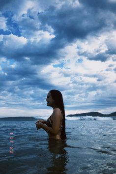 a woman standing in the water looking out to sea