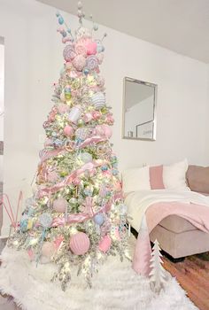 a decorated christmas tree in a living room with pink and white ornaments on the top