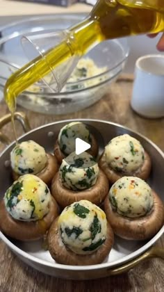 mushrooms with spinach and cheese in a pan being drizzled with olive oil