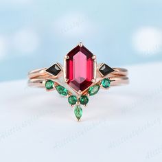 a close up of a ring with an emerald and red stone on it's side