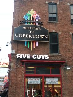 there is a sign on the side of this building that says, welcome to greektown five guys