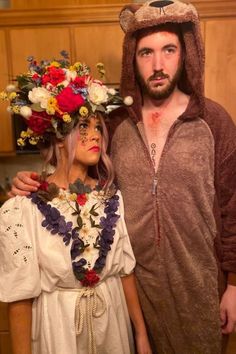 a man and woman dressed up as bears with flowers in their hair, standing next to each other