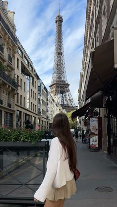 a woman is walking down the street in front of the eiffel tower